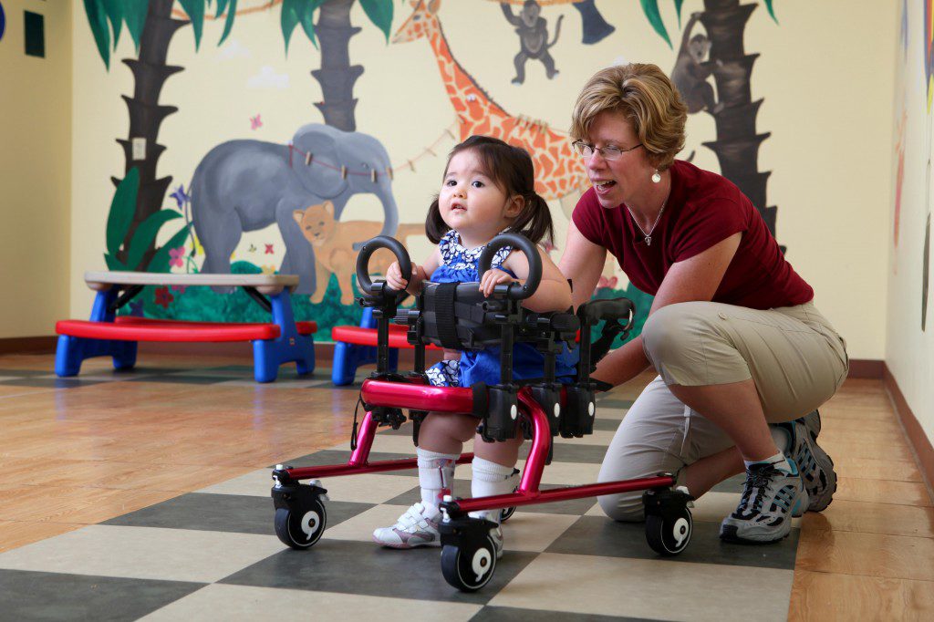 Little girl in a gait trainer, learning to walk.