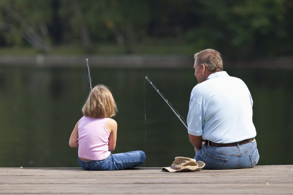 Grandfather and granddaughter fishing together.