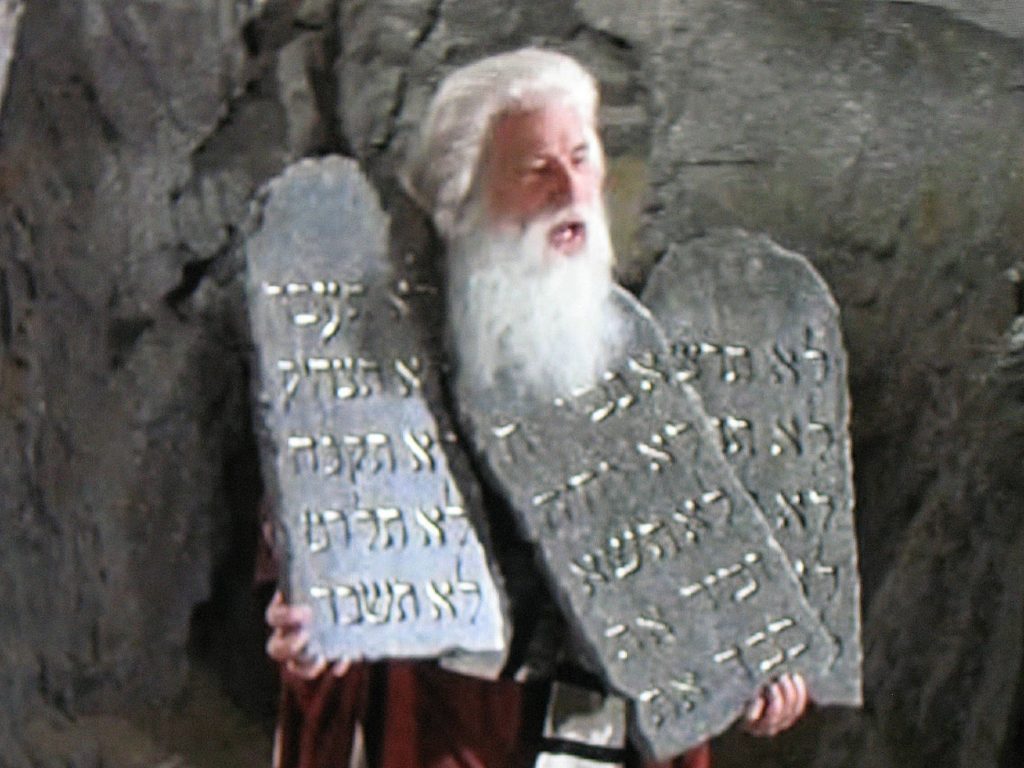 Mel Brooks holding the three tablets with 15 Commandments, dressed as Moses.