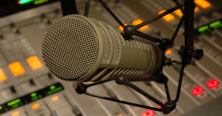 Image of a radio microphone in front of the radio studio mixing board.