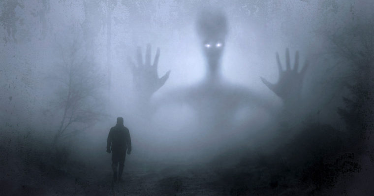 Image of a man walking towards a monster silhouetted in the mist.