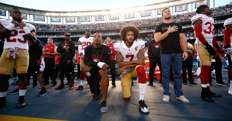 Football players kneeling in protest during the playing of the national anthem.