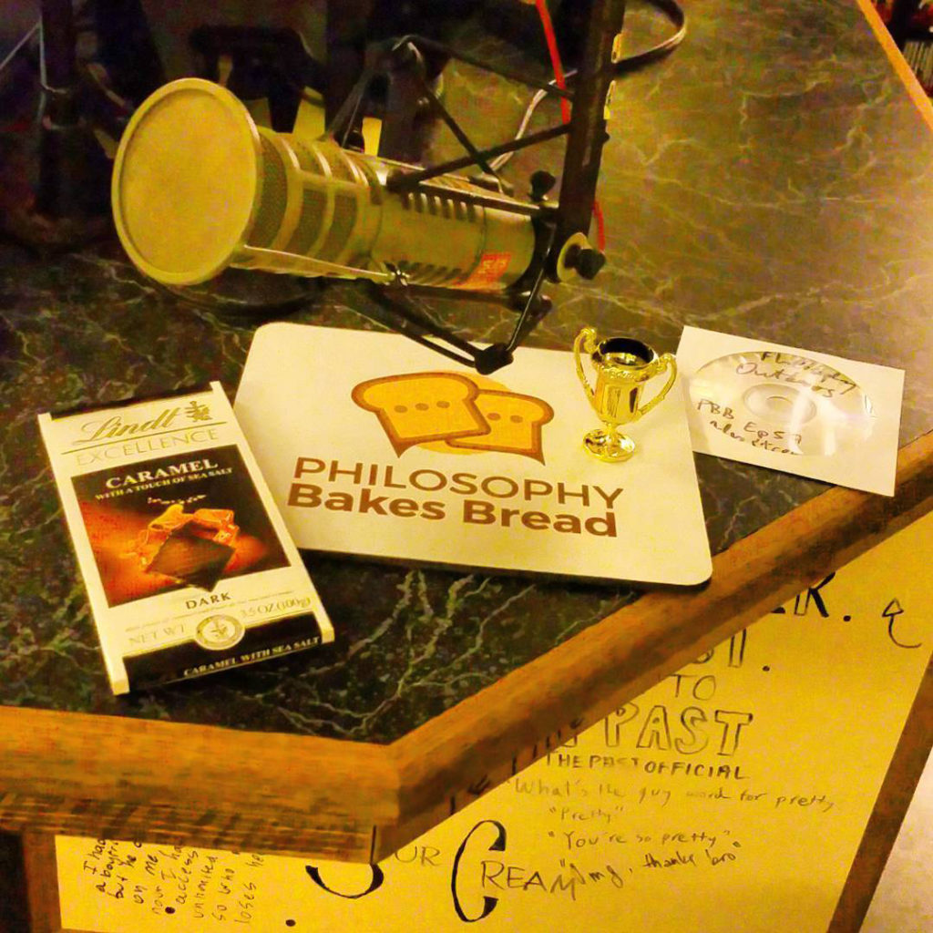 Photo of WRFL's trophy and chocolate bar, next to a station mic and a Philosophy Bakes Bread mousepad.