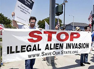 Protestors holding signs that read: "STOP Illegal Alien Invasion, wwwSaveOurState.org"