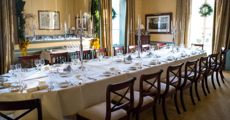 Photo of a table setting with all chairs empty, ready for a dinner party. 