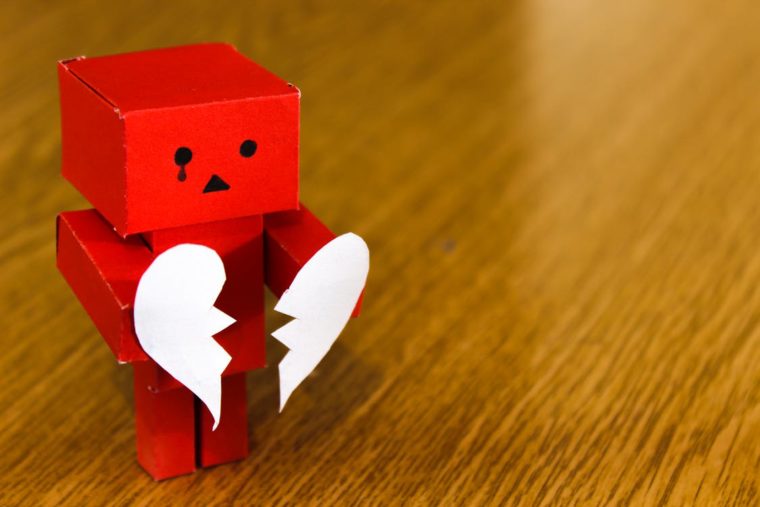 Photo of a box figure holding a broken heart.