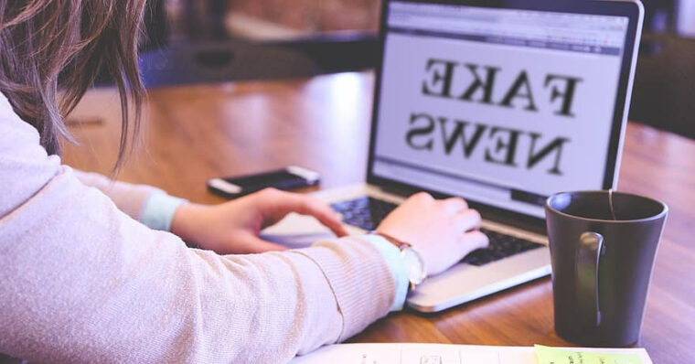 Image of a woman at her laptop on which the screen reads: 'Fake News.'